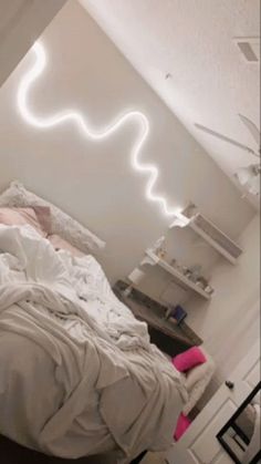 a bed with white sheets and pillows in a room next to a wall that has lights on it