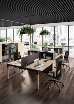 an office with wooden floors and desks in the middle, along with large windows