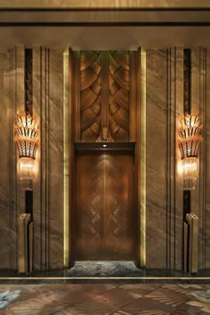 the entrance to a building with two lamps on either side and an elevator in front