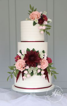 a three tiered wedding cake with flowers on top