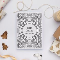 a merry christmas card surrounded by presents and wrapping paper on a white table with twine