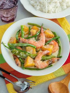 shrimp and pineapple stir fry with rice in a white bowl on a colorful table cloth