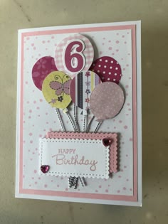 a birthday card with balloons on it and a number six in the middle, sitting on a table