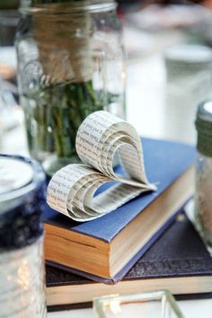 a couple of books sitting on top of each other next to a jar filled with flowers