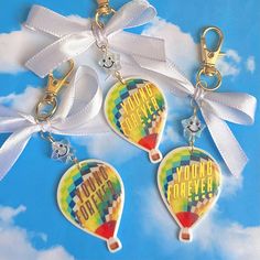 three hot air balloons with white ribbons tied around them on a blue sky and clouds background