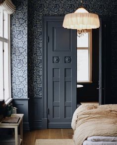 a bedroom with blue wallpaper and white bedding in front of an open door