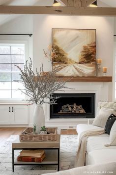 a living room with white furniture and a painting on the wall above the fire place