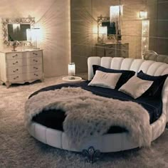 a bedroom with a round bed and white fur rugs on the floor in front of it