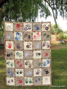 a quilt made to look like handprints on the ground in front of a tree