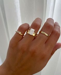 a woman's hand with two gold rings on it and a diamond in the middle