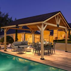 an outdoor living area next to a swimming pool at night with furniture and lights on