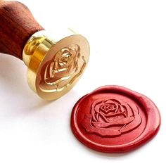 a wax seal with a rose on it next to a rubber stamp that has been carved