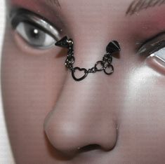 a woman's face with an eye chain attached to her nose