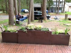 a woman sitting in a chair next to a large metal planter filled with plants