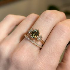 a woman's hand holding a ring with two different colored stones on it,