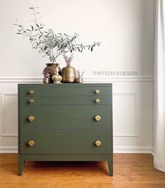 a green chest of drawers with two vases on top and one plant in the middle