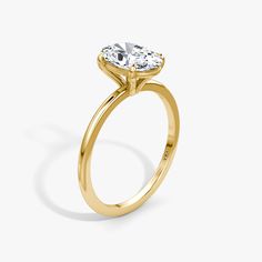 a yellow gold engagement ring with an oval cut diamond in the center, on a white background