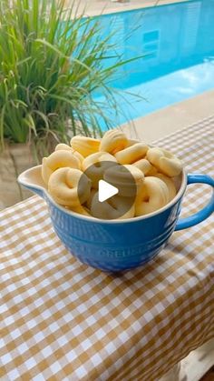 a bowl filled with donuts sitting on top of a table next to a pool