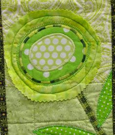 a green and white patchwork quilt with a large flower on it's center