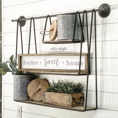 two metal shelves with plants and other items on them in front of a white wall