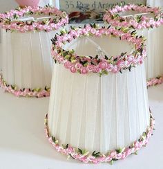 three lampshades decorated with pink flowers and green leaves on white table cloths