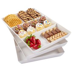 two trays filled with different types of pastries and strawberries on top of each other