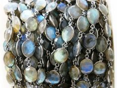 a close up view of a bracelet made out of silver chains and labradorite beads