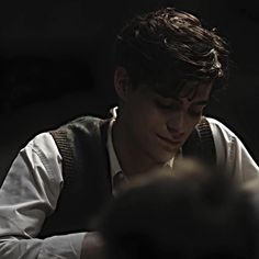 a young man sitting at a table looking down