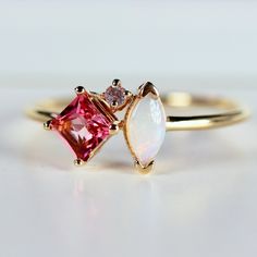 This beautiful, handmade unique cluster ring was made of 14k gold band, 14k gold prong settings. It's perfect as engagement ring or family birthstone statement piece. DETAILS ABOUT THE RING, MATERIAL AND STONES * 14k 1.3mm solid gold band and prongs. * 4x4mm princess cut natural pink tourmaline center stone * 6x3mm marquise cut real Australian opal * 1.5mm natural diamond ( 0.015 ct. weight) GH color SI clarity This ring can be personalized with the different birtstones. RING SIZE : US 7 READY TO SHIP! It can be resized in a week. ** All our raw materials are sourced from US-based companies for the quality and safety of our handmade products. *** This ring is handcrafted for you in our local studio in Redlands, California. We are a small workshop which specializes on handmade jewelry. *** 14k Gold Birthstone Cluster Ring, 14k Gold Cluster Ring With Accent Stones, 14k Gold Cluster Ring With Birthstone, Birthstone Cluster Ring Gift, 14k Gold Cluster Birthstone Ring, 14k Gold Cluster Sapphire Promise Ring, Cluster Birthstone Ring For Gift, Pink 14k Gold Cluster Ring With Gemstone, Unique 14k Gold Birthstone Promise Ring