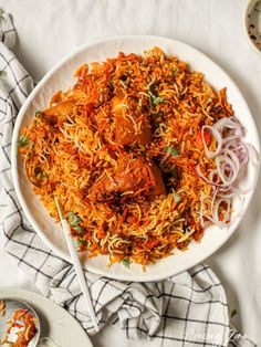 a white plate topped with shredded carrots next to a bowl of red onion slaw