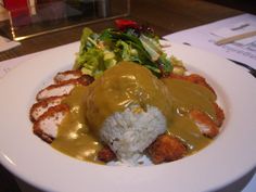 a white plate topped with rice and meat covered in gravy