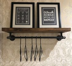 two framed pictures hang on a wall above a pair of hairdryers and hooks