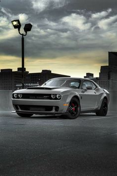 a white sports car parked in a parking lot next to a street light and tall buildings