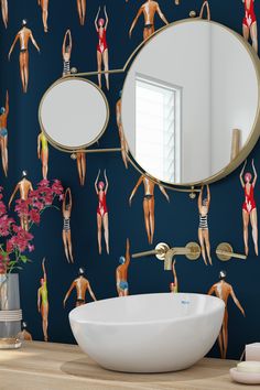 a bathroom with a sink, mirror and wallpaper that has women in bathing suits on it