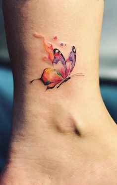 a colorful butterfly tattoo on the side of a woman's neck and foot,