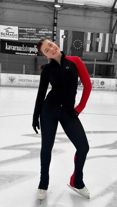 a woman in black and red skating on an ice rink with her hands behind her back