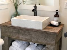 a white sink sitting on top of a wooden counter next to towels and a bottle