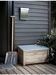 a wooden bench sitting on top of a wooden deck next to a mailbox and shovel