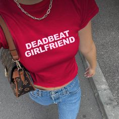 Deadbeat Gilrfriend Baby tee ✨ Step back into the iconic Y2K era with our "Deadbeat Girlfriend" Baby Tee, a perfect blend of 90s nostalgia and early 2000s style. This unhinged baby tee screams Y2K vibes, making a bold statement with its edgy and unapologetic slogan. Crafted from high-quality fabric, this baby tee offers both comfort and style, ideal for anyone looking to channel their inner 90s and 2000s fashion icon. Whether you're hitting up a y2k-themed party or just want to add a touch of Y2 Y2k Letter Print Top For Concerts, Y2k Style Letter Print Top For Concerts, Y2k Letter Print Concert Top, Fitted Text Print Top For Concert, Fitted Band Merch T-shirt With Logo Print, Fitted Letter Print Tops For Concerts, Red Y2k T-shirt For Streetwear, 90s Crew Neck Top For Concerts, Y2k Streetwear Slogan Tops