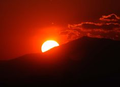 the sun is setting behind a mountain range