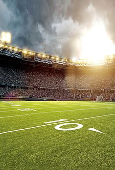 an empty football stadium with the sun shining down on it's field and cloudy sky