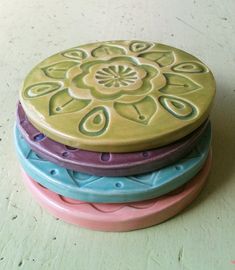 four ceramic plates stacked on top of each other in different colors and designs, one has a flower design