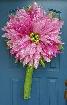 a large pink flower is attached to a blue door with green leaves and bells on it