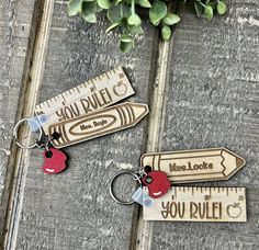 two personalized wooden keychains with measuring tape and red heart on each one