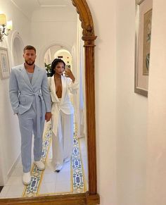 a man and woman standing in front of a mirror