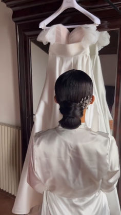 the back of a bride's dress hanging on a rack in front of a mirror