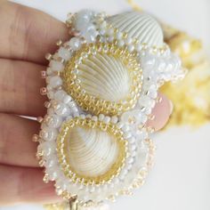 a close up of a person holding two seashells on a string with beads