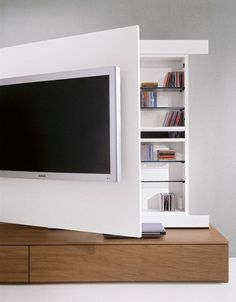 a flat screen tv mounted to the side of a white wall next to a book shelf