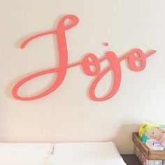 the name jojo is hanging on the wall above a bed in a room with white walls