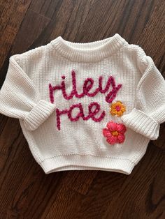 This listing is for an ivory sweater. It will have two flowers the same colors as pictured. Placement will depend on the name and where I think flowers will be placed best. We can discuss placement if you'd like after order is placed- just send me a message!  Please put the name you would like embroidered in the personalization box below.  I love customizations, message me to discuss other colors, or sizing! Name Sweater Baby, Baby Name Sweater, Name Sweater, Sweater Handmade, Take Home Outfit, Ivory Sweater, Baby Sweater, Gift Newborn, Personalized Embroidered